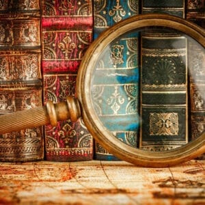 A magnifying glass is shown in front of books.