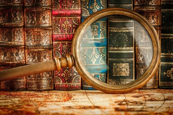 A magnifying glass is shown in front of books.