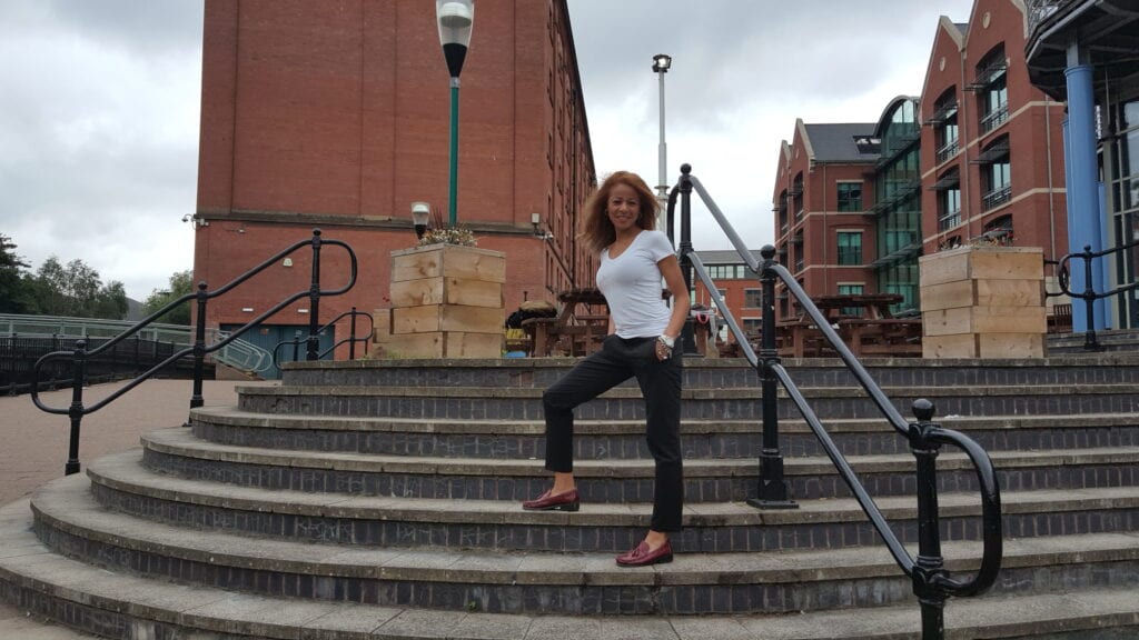 A woman in white shirt and black pants standing on stairs.