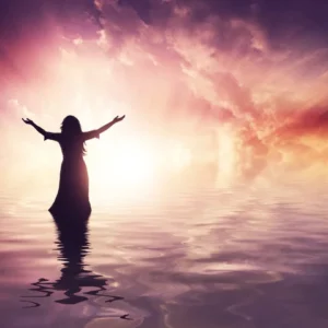 A woman standing in the water with arms outstretched.